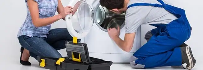 Washer repair technician inspecting a front-load washing machine with tools in Cincinnati, OH