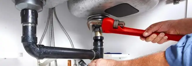 Garbage disposal repair technician tightening the sink drain and disposal connection in Cincinnati, OH