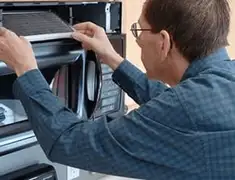 Appliance repair technician replacing a microwave vent filter in Cincinnati, OH