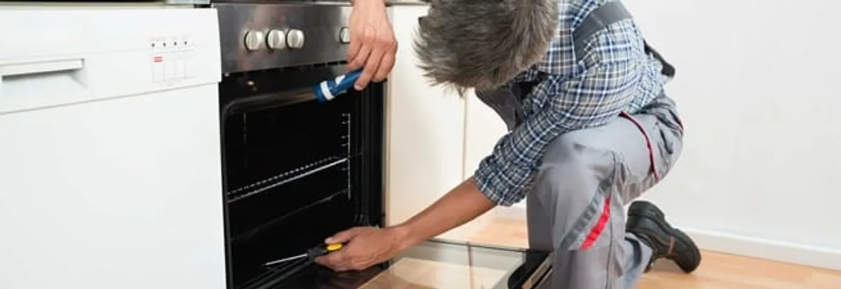 Oven repair technician inspecting and servicing an electric oven in Cincinnati, OH