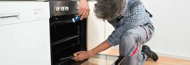 Oven repair technician inspecting and servicing an electric oven in Cincinnati, OH