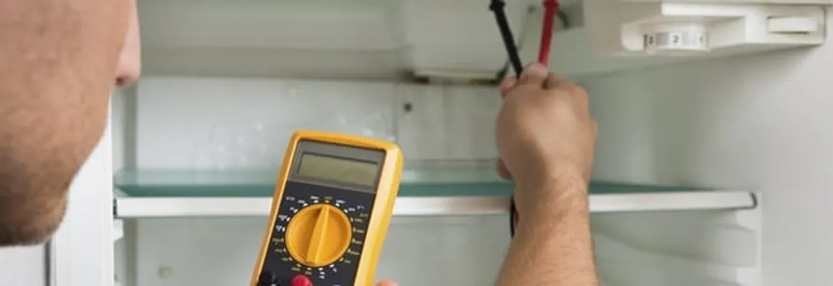Refrigerator repair technician testing electrical components with a multimeter in Cincinnati, OH